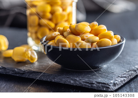 Lupini beans in brine. Pickled lupin in bowl on black table. 105143308