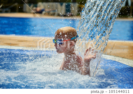 Young boy kid child eight years old splashing in swimming pool having fun leisure activity. Boy happy swimming in a pool. Activities on the pool, children swimming and playing in water, happiness and Young boy kid child eight years old splashing in swimming pool having fun leisure activity. Boy happy swimming in a pool. Activities on the pool, children swimming and playing in water, happiness and 105144011