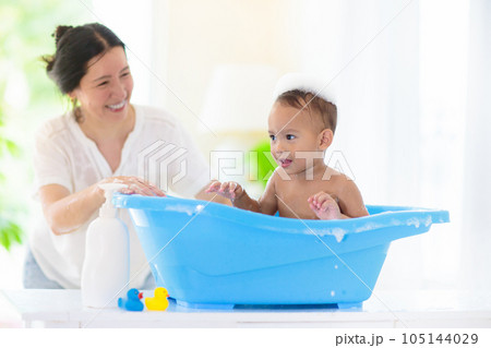 Baby boy in bath. Mother washing infant child. 105144029
