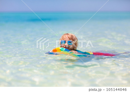 Kids surf on tropical beach. Vacation with child. 105144046