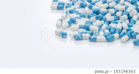 Blue-white antibiotic capsule pills on white background. Pile of antibiotic drug. Antibiotic drug resistance. Prescription drugs. Healthcare and medicine. Pharmaceutical industry. Pharmacy product. 105146363