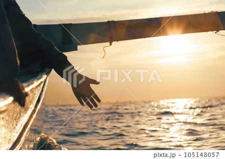 Silhouette of a hand from a boat on a sunset background Silhouette of a hand from a boat on a sunset background 105148057