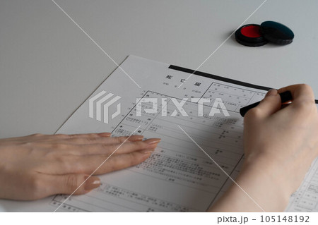 死亡届に判を押す手元 105148192