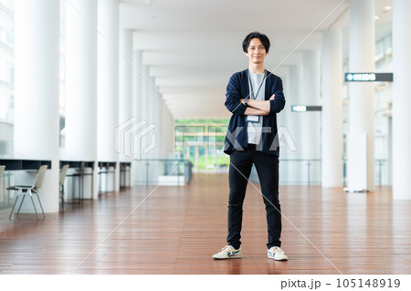 オフィスの廊下で腕組みをする若い男性 105148919