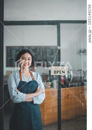 Portrait of happy waitress standing at restaurant entrance with open sign, Portrait of young business woman attend new customers in her coffee shop. 105149150
