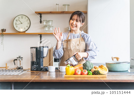 朝キッチンでコーヒーを淹れるエプロン姿のアジア人女性 105151444