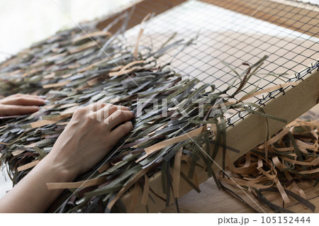 Woman weaving camouflage military mesh for helmet. 105152444