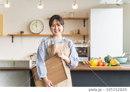 キッチンでエプロン姿で働く家政婦・家事代行・料理代行スタッフのアジア人女性 キッチンでエプロン姿で働く家政婦・家事代行・料理代行スタッフのアジア人女性 105152820