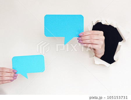 Dialogue icon. Blank speech bubble. Female hands inside breakthrough paper hole showing blue message mockup on white torn background with empty space. 105153731
