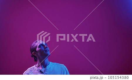 Surprised face. Neon light portrait. Special offer. Blue purple color impressed smiling guy reading invisible text on dark futuristic copy space commercial background. 105154380