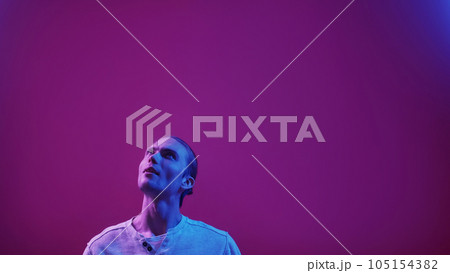 Neon people. Advertising background. Information presentation. Blue purple color light curious impressed guy reading invisible text on dark empty space. 105154382