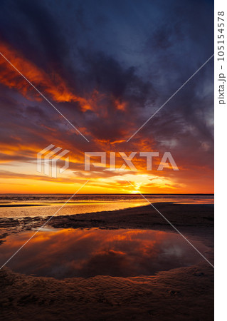 sunset sky with reflections in water, sunlight and colored orange clouds. 105154578