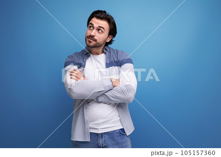 pensive brunette guy in a model appearance dreams on a studio background 105157360