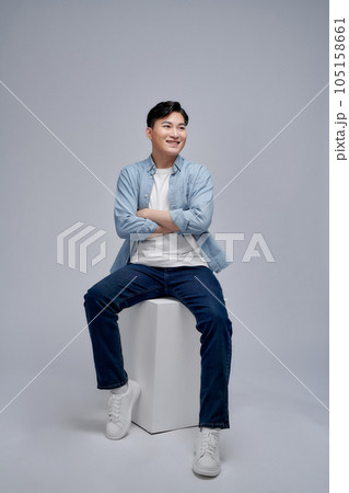 Happy and confident Asian man relaxing while sitting on the chair on white background Happy and confident Asian man relaxing while sitting on the chair on white background 105158661