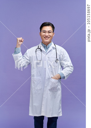 Portrait of beautiful young female doctor in white medical jacket isolated on purple background. 105158697