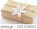 Christmas and New Year background. Gift box wrapped in kraft paper with jute cord. Decorated with a crocheted snowflake 105159022