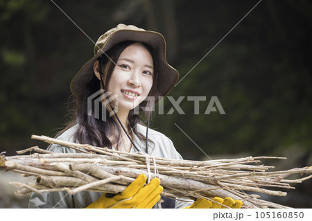 キャンプ場で焚き火用の枝を運ぶ若い女性 105160850