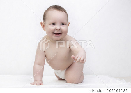 Kid with a smile on a white background. A happy six month old boy crawls on the bed and laughs. Conceptual photo of fatherhood and motherhood. Kid with a smile on a white background. A happy six month old boy crawls on the bed and laughs. Conceptual photo of fatherhood and motherhood. 105161185