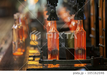 Glassworks. Glass industry. The process of making glass bottles.Molten hot glass containers on conveyor belt 105162046