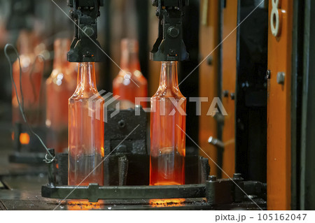 Glassworks. Glass industry. The process of making glass bottles.Molten hot glass containers on conveyor belt 105162047