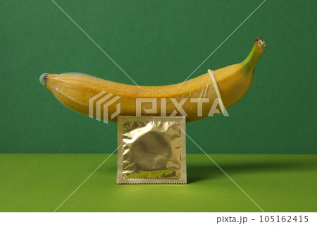 A condom on a banana on a green background 105162415