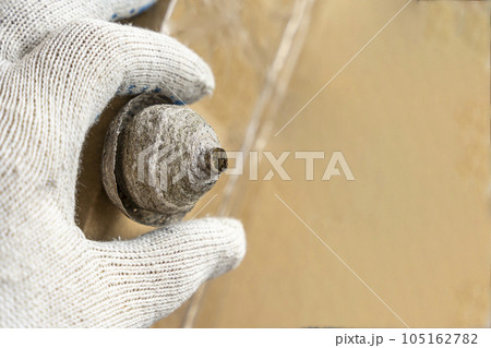 man's hand in a protective work glove removes a wasps nest 105162782