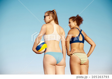 Back view image of sportive young women, with fit, slim body in swimsuit standing with volleyball ball over blue sky background Back view image of sportive young women, with fit, slim body in swimsuit standing with volleyball ball over blue sky background 105163793