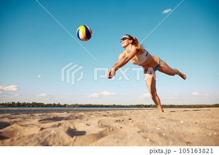 Dynamic image of young woman in motion, playing beach volleyball, hitting ball and falling down on sand Dynamic image of young woman in motion, playing beach volleyball, hitting ball and falling down on sand 105163821