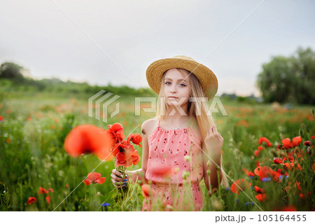 Ukrainian Beautiful girl in poppies field and wheat. outdoor portrait. Child collecting poppies and cornflower in summer field. Blooming Poppies memory symbol. 105164455