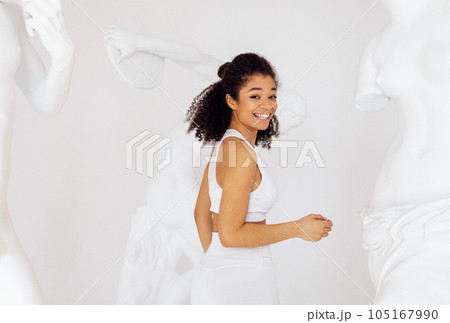 Laughing happy curly haired mixed race girl raises arm and shows biceps 105167990