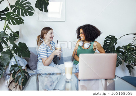 Attractive multiracial teenagers drink cappuccino and chat. Funny teen girls talk and have good time together. 105168659