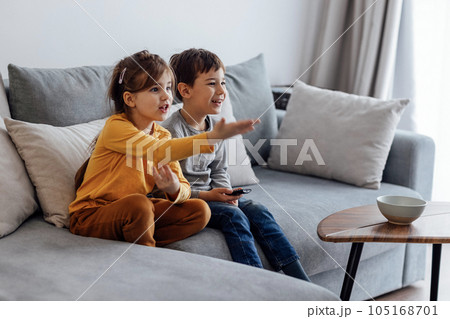 Cute girl and boy laughing and choosing cartoons in tv 105168701