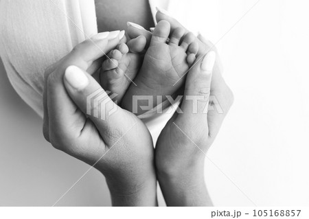 The palms of the father, the mother are holding the foot of the newborn baby on white background. Feet of the newborn on the palms of the parents. Photography of a child's toes, heels and feet. 105168857