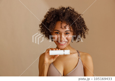 Young woman holding bottle with beauty product in studio Young woman holding bottle with beauty product in studio 105169433
