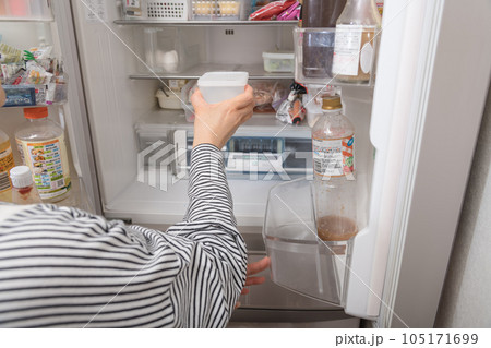 【冷蔵室からタッパを取り出す主婦】 105171699