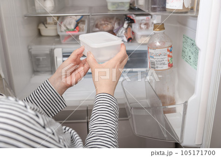 【冷蔵室からタッパを取り出す主婦】 105171700