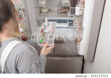 【冷蔵室からトレイを取り出す主婦】 105171701