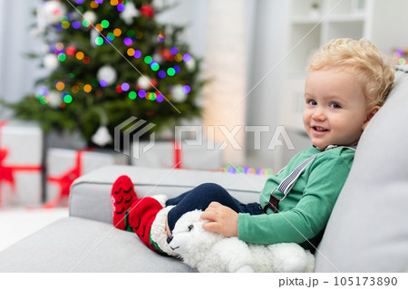 A little boy holds a plush toy while sitting on the couch 105173890