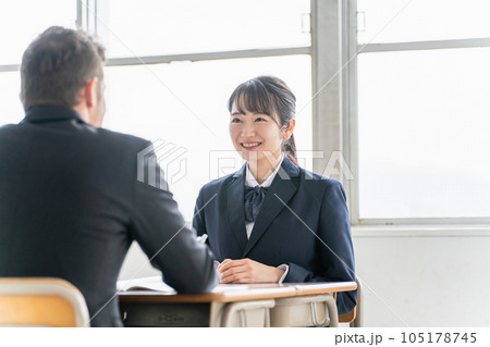 学校で志望校について進路相談・二者面談・面接練習を行う教師と笑顔のアジア人の高校生 学校で志望校について進路相談・二者面談・面接練習を行う教師と笑顔のアジア人の高校生 105178745