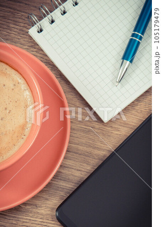 Mobile phone, coffee with milk and notepad for writing notes. Work or relaxation 105179479