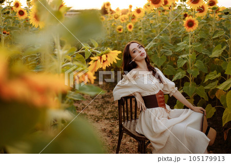 Woman in a dress in a field of sunflowers on a chair 105179913