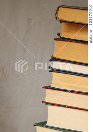 Pile of books stacked on a gray background with space for copy 105179916