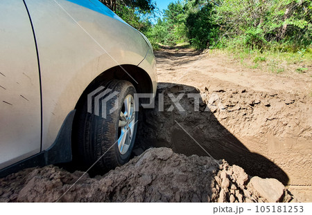 The car hit the front wheel in a deep hole on the road in the forest strip. The car hit the front wheel in a deep hole on the road in the forest strip. 105181253