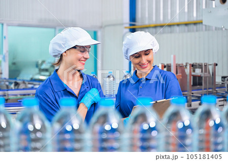 Bottling factory worker inspecting quality of water bottles before shipment. Reverse osmosis system used in plant. water purity and maintaining quality control in bottling process. High quality photo 105181405
