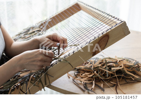 Woman weaving camouflage military mesh for helmet. 105181457