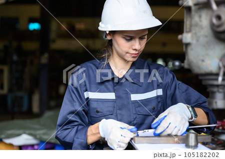 Female worker with safety hard hat working at manufacturing 105182202