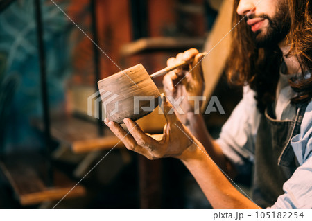 Potter making jug of clay on potter wheel circle in workshop Potter making jug of clay on potter wheel circle in workshop 105182254
