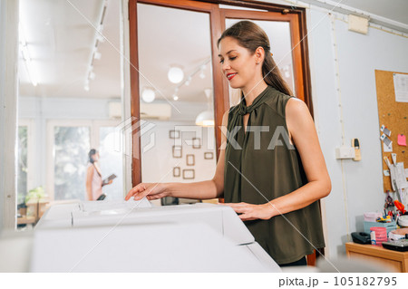 Confident secretary using modern printer and working at company Confident secretary using modern printer and working at company 105182795