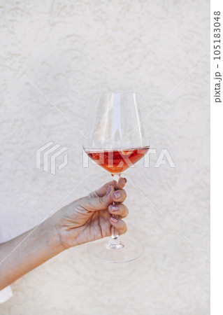 A close up of an elegant champagne glass with a long stem standing on a woman palm with a neat manicure 105183048