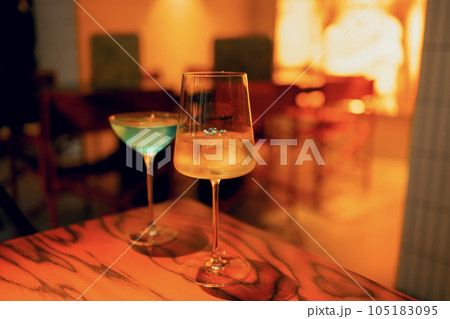 Two delicious ice cold cocktails in exquisite glasses stand on a wooden table in a restaurant. 105183095